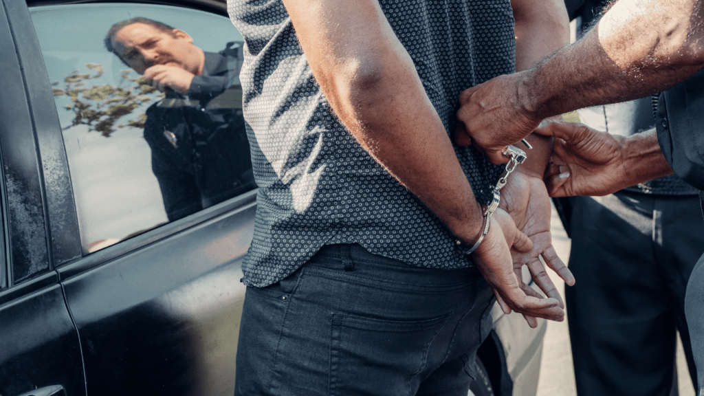 a person being arrested by police in front of a car