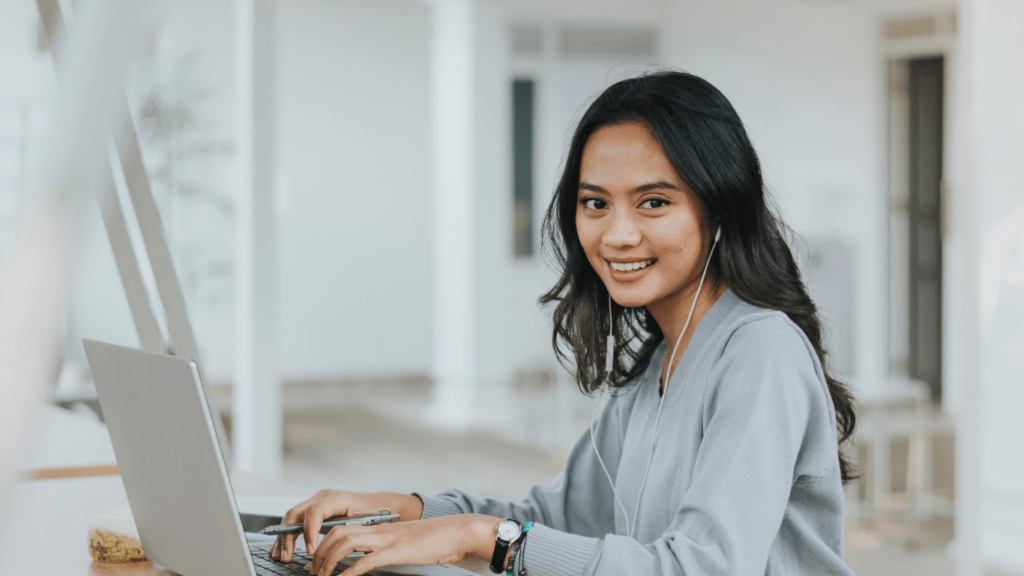 a smiling person working on a laptop