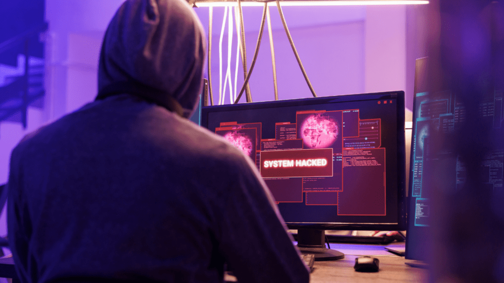 a person in a hoodie sitting in front of a computer screen