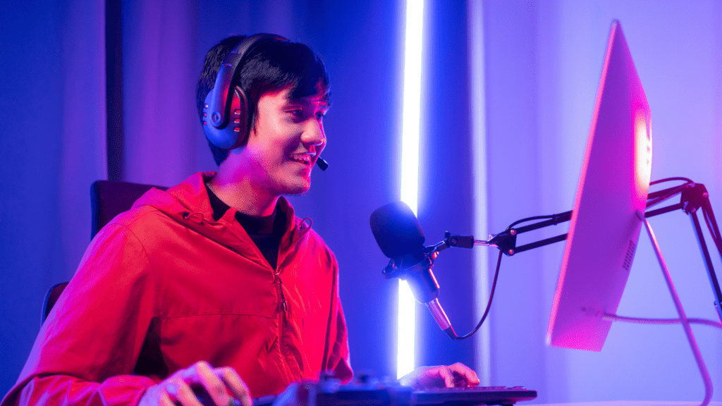 a person in a red shirt is sitting in front of a computer with headphones on