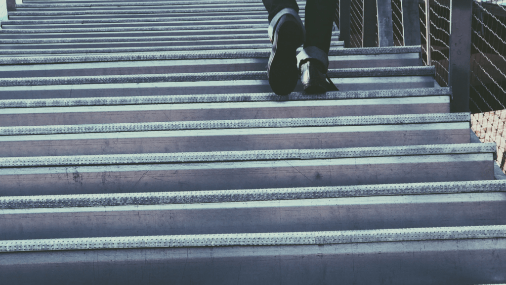 a person in a suit and tie walking up a set of stairs